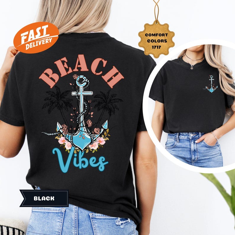K&ouml;nnte beinhalten: Schwarzes T-Shirt mit Strandmotiv. Auf der R&uuml;ckseite steht das Wort "BEACH" in korallenfarbenen Buchstaben &uuml;ber einem hellblauen Anker mit floralen Akzenten und dem Wort "Vibes" in t&uuml;rkisfarbener Schrift. Ein kleineres Ankerdesign befindet sich auf der Vorderseite.