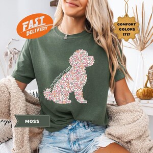 May include: A green t-shirt with a floral patterned golden doodle silhouette. The text "Goldendoodle Mom" is printed on the shirt.