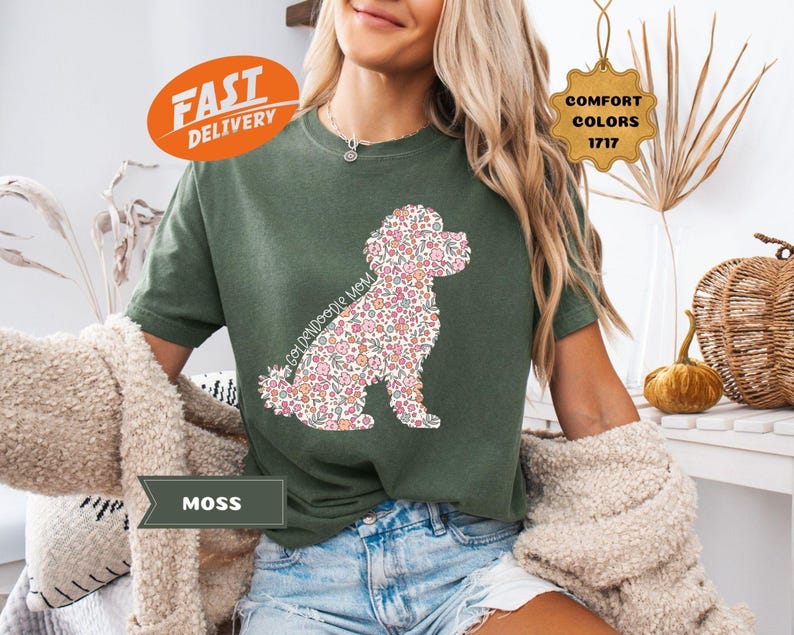 May include: A green t-shirt with a floral patterned golden doodle silhouette. The text "Goldendoodle Mom" is printed on the shirt.