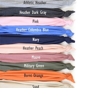 K&ouml;nnte beinhalten: Eine Sammlung gefalteter Stoffmuster in verschiedenen Farben, darunter Kelly Green, Athletic Heather und Heather Dark Gray. Jedes Muster ist mit seinem Farbnamen beschriftet. Das Bild zeigt eine Reihe von Farbt&ouml;nen, von Pink bis Marineblau und Orange bis Kastanienbraun.