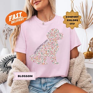 May include: Pink t-shirt with a floral doodle of a Goldendoodle dog and the text "Goldendoodle Mom".