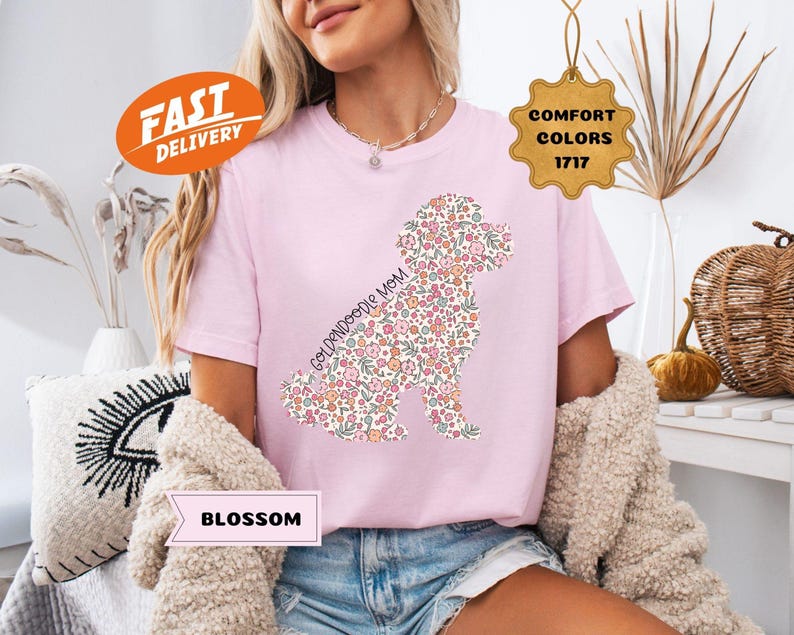May include: Pink t-shirt with a floral doodle of a Goldendoodle dog and the text "Goldendoodle Mom".