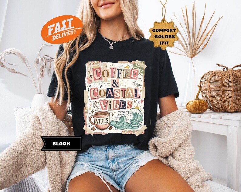 May include: Black t-shirt with the words "Coffee & Coastal Vibes" in a colorful, collage-style design. The graphic includes a coffee cup, waves, and other coastal elements. The shirt is a Comfort Colors 1717.