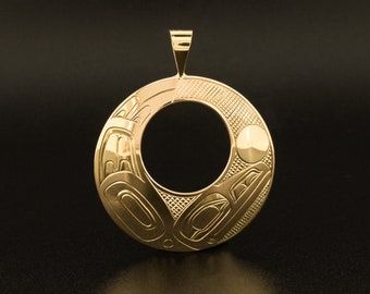 May include: A gold pendant with a circular design featuring intricate carvings of a stylized animal, possibly a bird or a fish. The pendant has a large circular opening in the center.