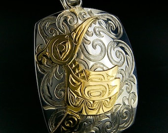 May include: A silver pendant with a gold hummingbird design. The hummingbird is stylized with intricate details and is surrounded by a swirling floral pattern.