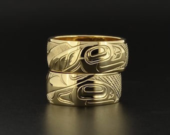 May include: Two gold rings with intricate carvings of a stylized animal design. The rings are stacked on top of each other.