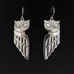 May include: A pair of silver owl earrings with detailed wings and a textured finish.