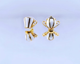 May include: A pair of gold and white teapot and cup earrings. The earrings are small and delicate, and they would make a great gift for a tea lover.