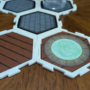 Pode incluir: Peças de jogo modulares com bordas brancas e vários designs. Algumas peças apresentam grão de madeira, outras padrões de pedra e uma tem um portal verde brilhante. As peças são dispostas em uma superfície de madeira.