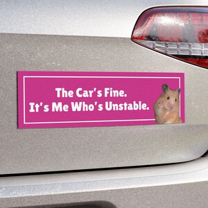 May include: A pink bumper sticker with white text that reads "The Car's Fine. It's Me Who's Unstable." A hamster is peeking out from the right side of the sticker.