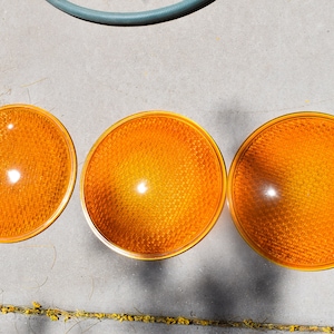 May include: Three round, orange traffic reflectors with a textured surface.