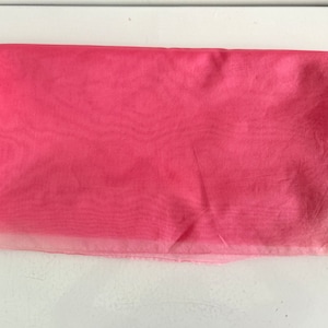 May include: A piece of pink sheer fabric, folded in half, with a lighter pink edge.
