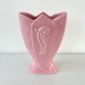 May include: A pink ceramic vase with a floral design. The vase is shaped like a tulip and has a wide opening.