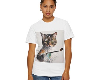 Może przedstawiać: Biały t-shirt z grafiką kota trzymającego pędzel. Kot jest brązowy, czarny i biały. Kot patrzy na widza.