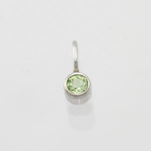May include: A silver pendant with a round green gemstone.