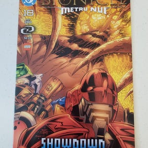Może przedstawiać: Okładka komiksu Bionicle Metru Nui #18, opublikowanego w maju 2004 roku. Na okładce czerwony robot na pierwszym planie ze słowem &bdquo;SHOWDOWN&rdquo; w kolorze niebieskim. Tło ma ognisty, pomarańczowo-brązowy wz&oacute;r.
