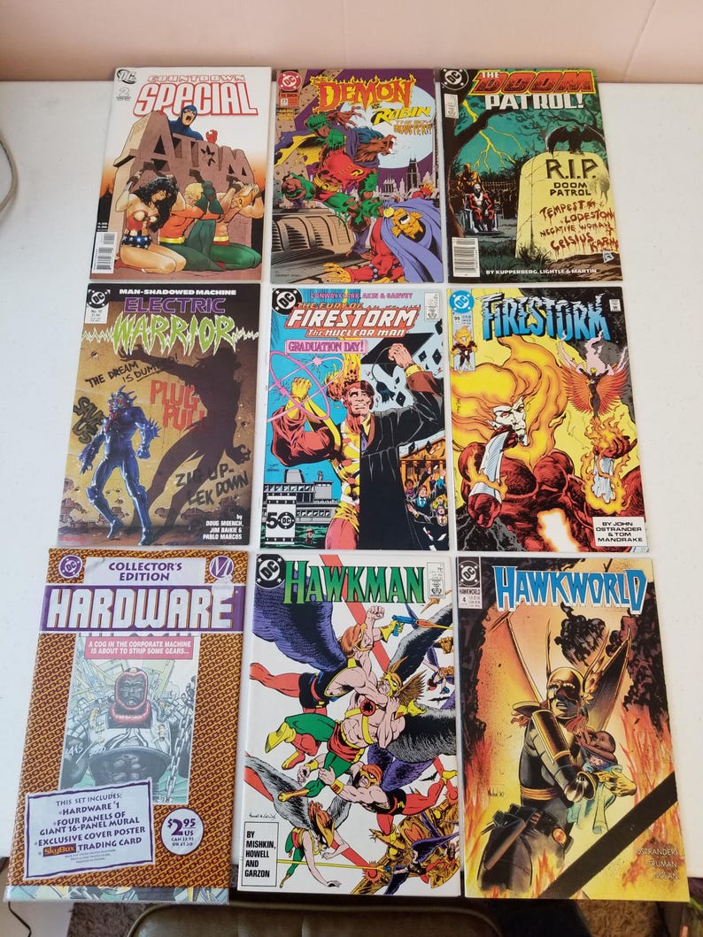 Może przedstawiać: Kolekcja komiks&oacute;w vintage DC Comics. Okładki prezentują żywe ilustracje i tekst, w tym tytuły takie jak "Special", "Demon", "Firestorm" i "Hawkman". Komiksy są ułożone na jasnej powierzchni.