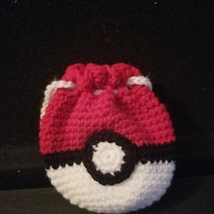 May include: A red, white, and black crocheted drawstring bag shaped like a Pokeball.