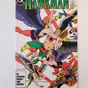 Może przedstawiać: Vintage okładka komiksu Hawkman, przedstawiająca dynamiczną scenę akcji z uskrzydlonymi postaciami w locie. Okładka ma logo DC Comics i tytuł "Hawkman" dużymi zielonymi literami. Grafika jest kolorowa, z postaciami w kolorze czerwonym, ż&oacute;łtym i zielonym.