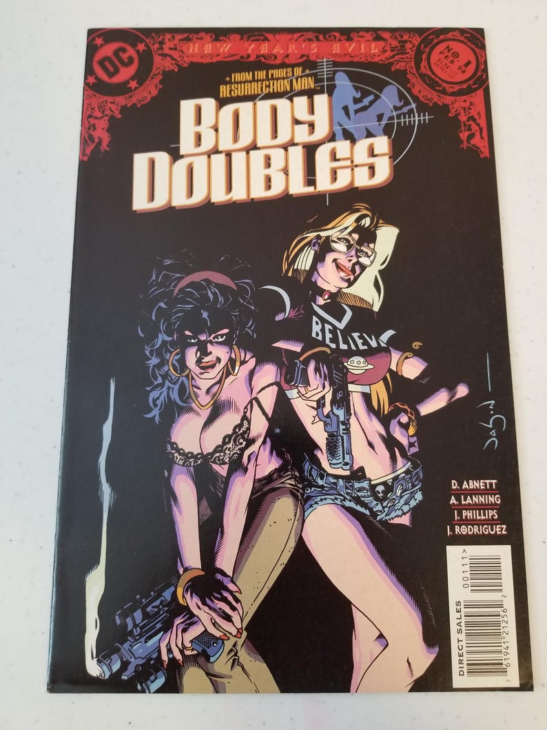 Może przedstawiać: Okładka komiksu "Body Doubles" z dwiema kobietami trzymającymi broń. Okładka ma czarne tło z tytułem dużymi, pogrubionymi literami. Logo DC Comics znajduje się w lewym g&oacute;rnym rogu. Widoczny jest r&oacute;wnież tekst "From the pages of Resurrection Man".