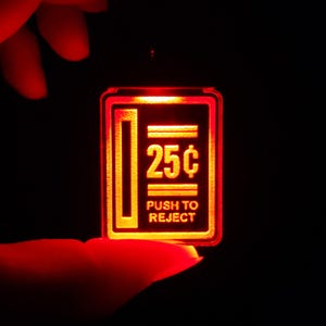 May include: A red illuminated sign with the text "25¢ PUSH TO REJECT" in white.