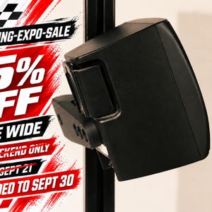 May include: A black speaker mounted on a vertical black metal frame. The image features red and white text that reads SIM-RACING-EXPO-SALE, 15% OFF, STORE WIDE, THIS WEEKEND ONLY, ENDS SEPT 21, and EXTENDED TO SEPT 30 with a checkered flag graphic.