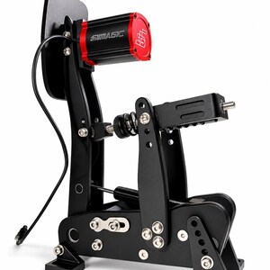 Peut inclure: Un ensemble de pédales de course en métal noir comprenant un boîtier de moteur cylindrique rouge et noir avec le texte SIMAGIC imprimé sur le côté. Le dispositif comprend un bras de pédale vertical, un mécanisme à ressort horizontal et des boulons argentés.