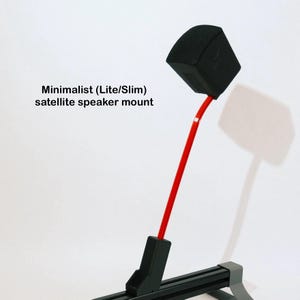 May include: A satellite speaker mount featuring a black speaker housing attached to a thin, angled red metal arm. The base is a black horizontal rail with grey end caps. Text on the image reads: Minimalist (Lite/Slim) satellite speaker mount.
