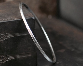 May include: A silver bangle bracelet with a hammered finish. The bracelet is simple and elegant, and would make a great gift.