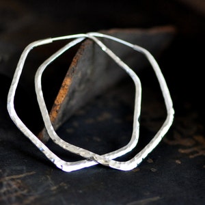 May include: A pair of silver octagon-shaped hoop earrings with a hammered texture.