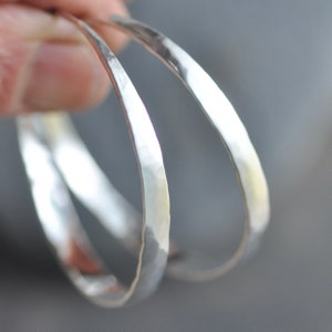 May include: Two silver hammered bangle bracelets, stacked on top of each other.