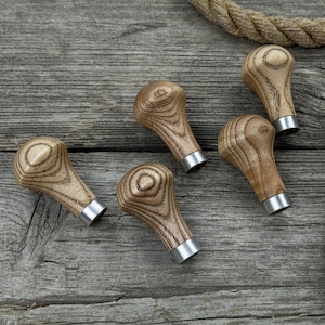 May include: Five wooden tool handles with a silver metal base. The handles are a light brown color with a wood grain pattern.