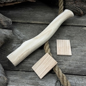 May include: A light-colored wooden axe handle with a curved shape. Two small wooden squares are also shown in the image.