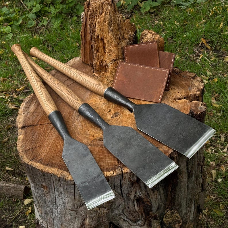Top view of flat timber slick chisels and leather sheaths on a bench, clean layout for surface leveling
