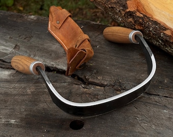 Halvrundad dragkniv. Vasst blad i kolstål, handtag i askträ, läderslida. Dragkniv för skedskärning. Handsmidd rakkniv.