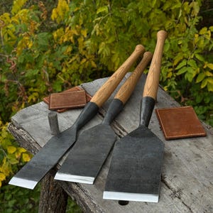 Angled view of timber slick chisels on a workbench with leather sheaths nearby, professional tools layout
