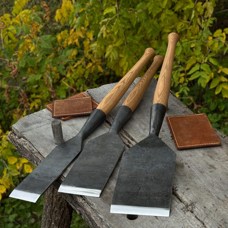 Angled view of timber slick chisels on a workbench with leather sheaths nearby, professional tools layout