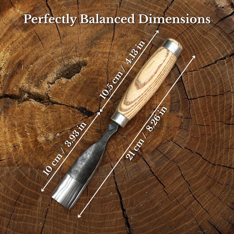 May include: A wood carving gouge with a light-coloured wooden handle and a dark metal blade. The tool features text stating Perfectly Balanced Dimensions and includes measurements of 10.5 cm for the handle, 10 cm for the blade, and 21 cm in total length.