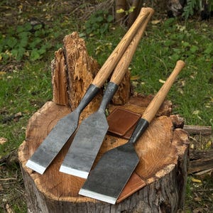 Side profile of large timber slick chisels showing straight edges and wide blades for framing