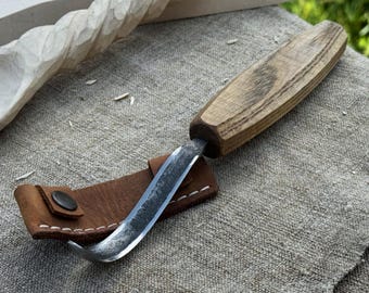 Handgesmeed haakmes voor het snijden van lepels. Scherp mes van koolstofstaal, essenhouten handvat, leren schede. Beginnersmes voor houtsnijwerk.