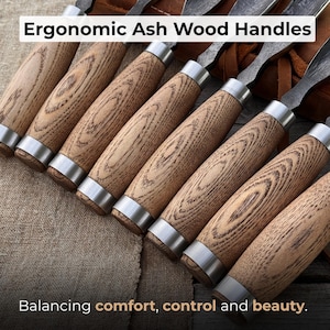 May include: A set of carving tools featuring light brown ash wood handles with visible grain patterns and silver metal ferrules. The text Ergonomic Ash Wood Handles and Balancing comfort, control and beauty is visible on the image.