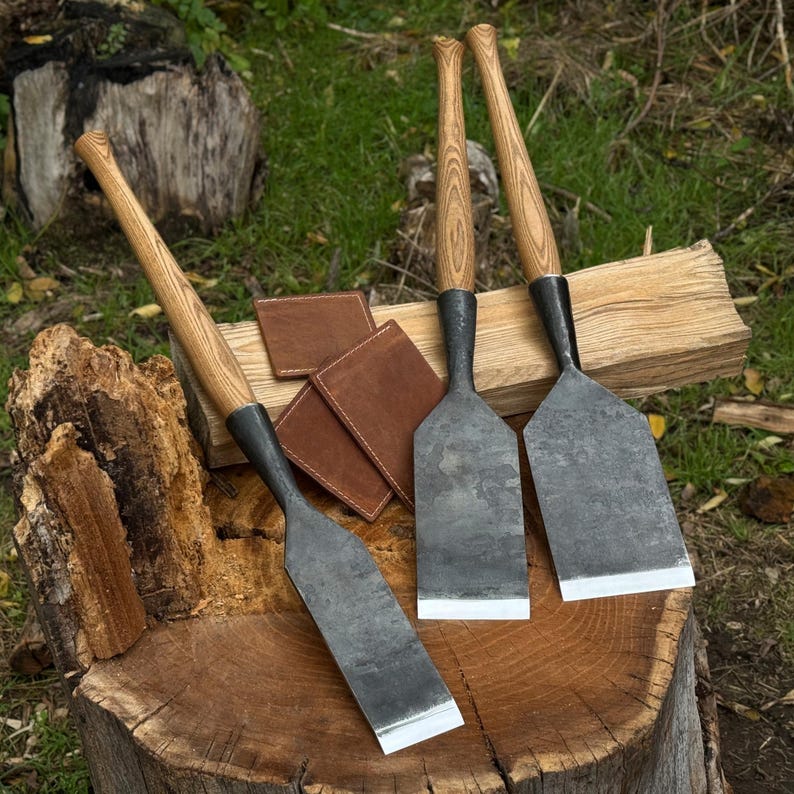 Three timber slick chisels on a workbench with leather sheaths beside them, professional chisel set for framing work