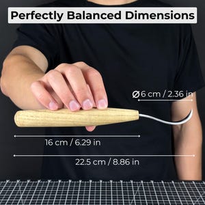 May include: A wood-handled carving knife with a curved blade, held in a person's hand. The text "Perfectly Balanced Dimensions" is at the top. The knife is 6.29 inches long, with a blade length of 8.86 inches. The handle is 2.36 inches in diameter.