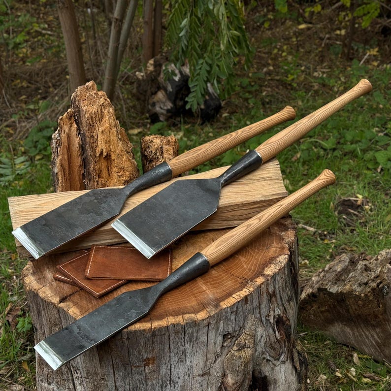 Outdoor stump view showing three chisels aligned side by side, framing chisels for joinery work