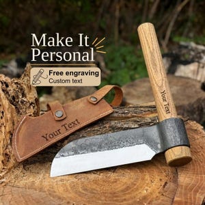 Pode incluir: Um machado de mão com uma lâmina de metal escuro martelado e um cabo de madeira clara com o texto Your Text. Inclui uma bainha de couro castanho com fecho de pressão e o texto Your Text. A sobreposição de texto diz Make It Personal.