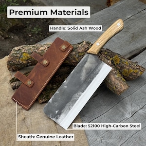 Puede incluir: Un cuchillo de carnicero con mango de madera maciza de fresno y hoja de acero con alto contenido de carbono 52100. El cuchillo descansa junto a una funda de cuero marr&oacute;n. El texto "Premium Materials" est&aacute; en la parte superior de la imagen.