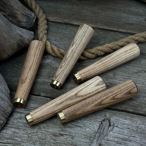 以下が含まれることがあります： 明るい茶色の仕上げと真鍮色の金属チップが付いた、5つの木製家具の脚のコレクション。 脚は風化した木製の表面に配置され、背景にはロープがあります。