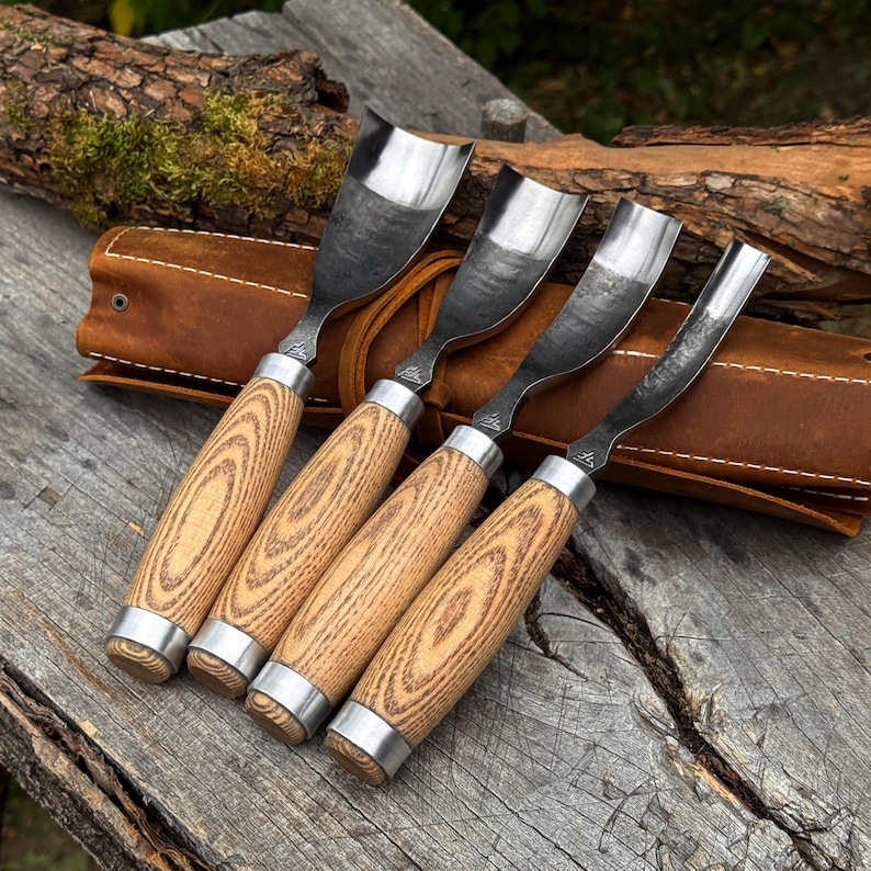 Pu&ograve; includere: Un set di quattro sgorbie per intaglio con lame metalliche curve e manici in legno chiaro con venature a vista. Ogni utensile presenta una ghiera in metallo e un piccolo logo stampato vicino alla base della lama. Il set &egrave; riposto in un rotolo in pelle.