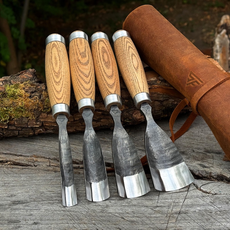 Puede incluir: Cuatro gubias para tallar madera con mangos de madera clara y virolas de metal plateado, con hojas de acero oscuro y texturizado de diferentes anchos. Un estuche de cuero marr&oacute;n para herramientas con un logotipo estampado acompa&ntilde;a al set.