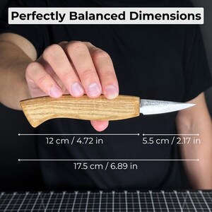 Wood carving knife held by craftsman with marked measurements, showing compact size, blade length, and control for fine carving.